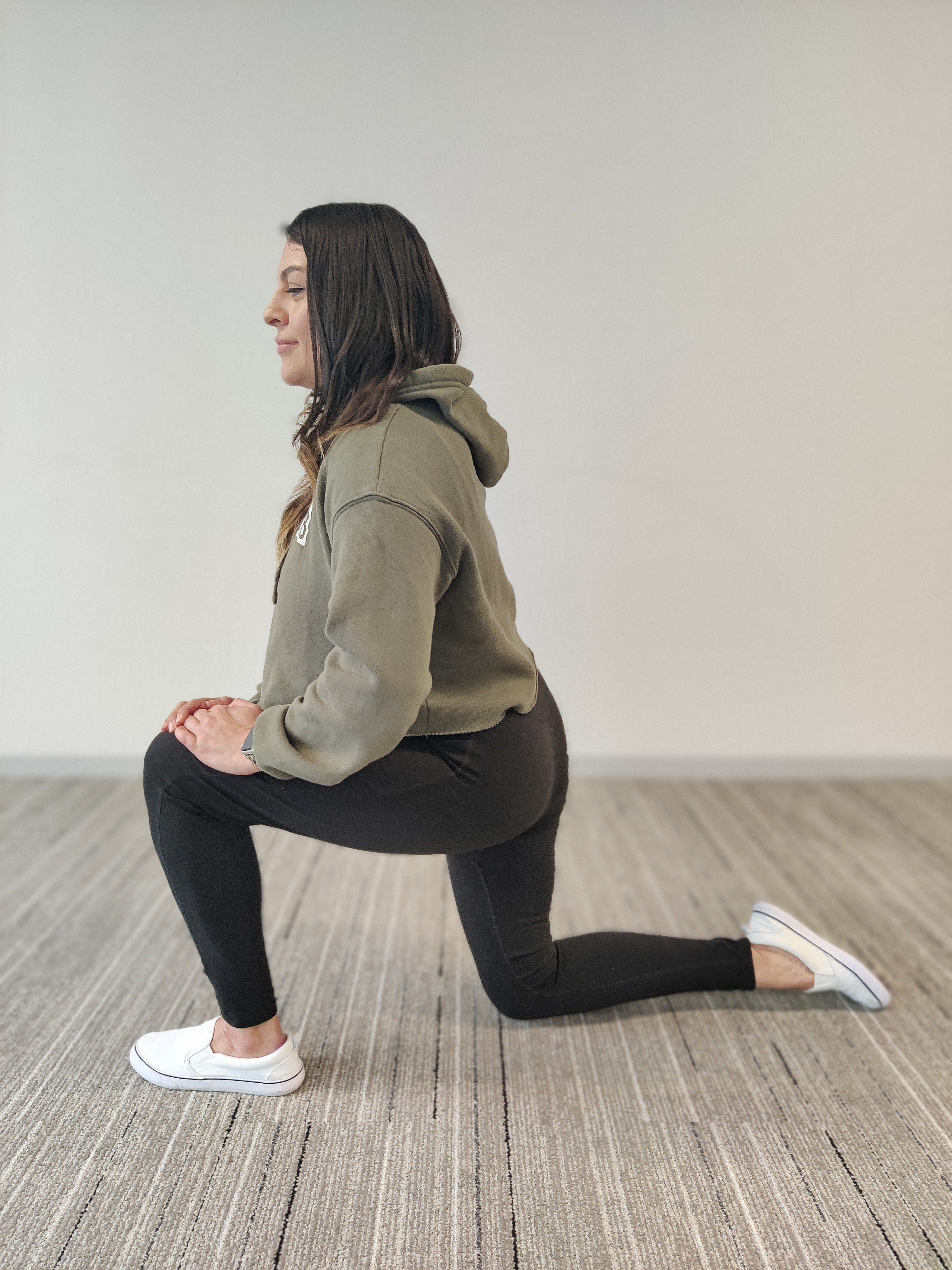 female in green StretchLab sweater doing a reverse lunge stretch on floor